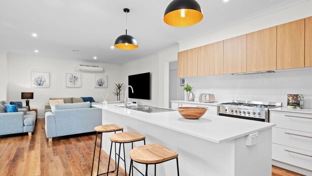 A modern kitchen with a central island, wooden cabinets, and a large stove. - Aerial Beach House - Beach & Golf (Torquay)
