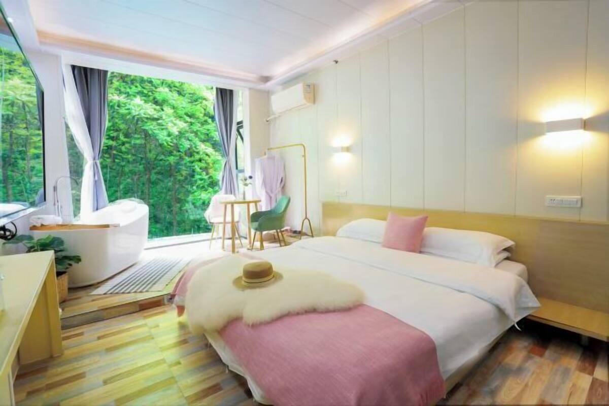 Une chambre d’hôtel avec un lit, un bureau, une chaise et une vue sur la verdure.