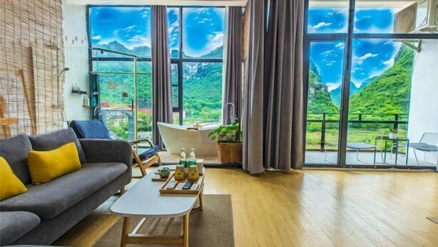 A modern living room with a sofa, coffee table, and a large window with a scenic view. - Yangshuo Xitian Yueshan Homestay (Eternal Love Store) (Yangshuo)