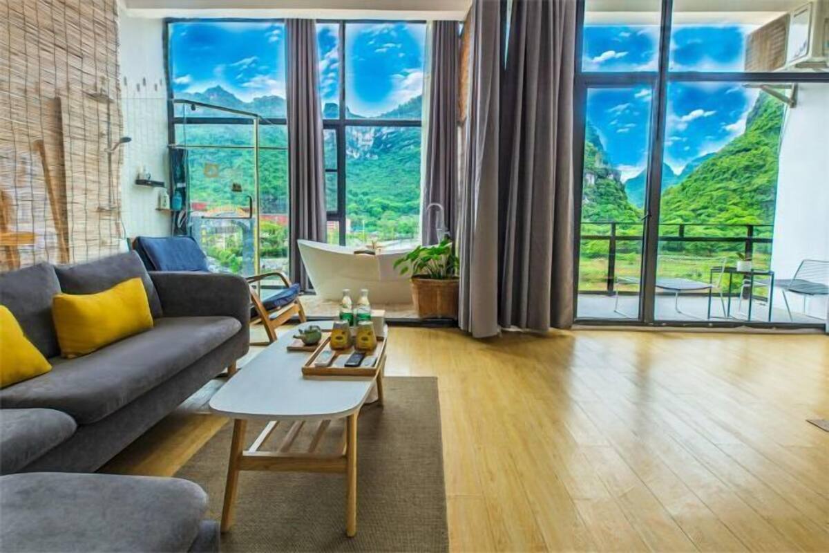 Un salon moderne avec un canapé, une table basse et une grande fenêtre offrant une vue panoramique.