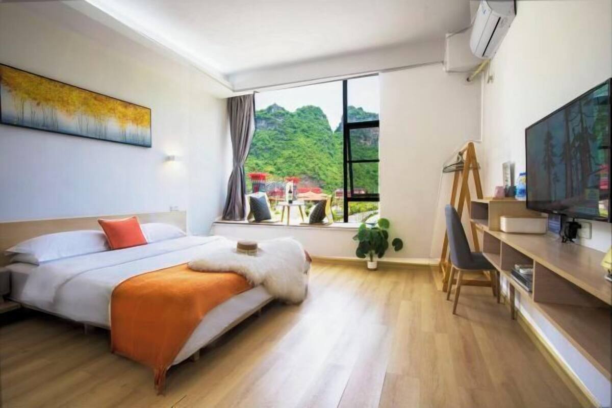Une chambre d’hôtel moderne équipée d’un lit, d’un bureau avec un ordinateur, d’une télévision et d’une fenêtre donnant sur les montagnes.