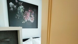 A bedroom with a bed, a wardrobe, and a painting on the wall. - Apartment 1 Marktkirchhof - Hotel Theophano (Quedlinburg)