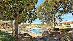 Un sendero de piedra que conduce a una piscina rodeada de árboles y un muro de ladrillo.
