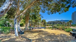 Un parc avec un trampoline, des bancs et des arbres.