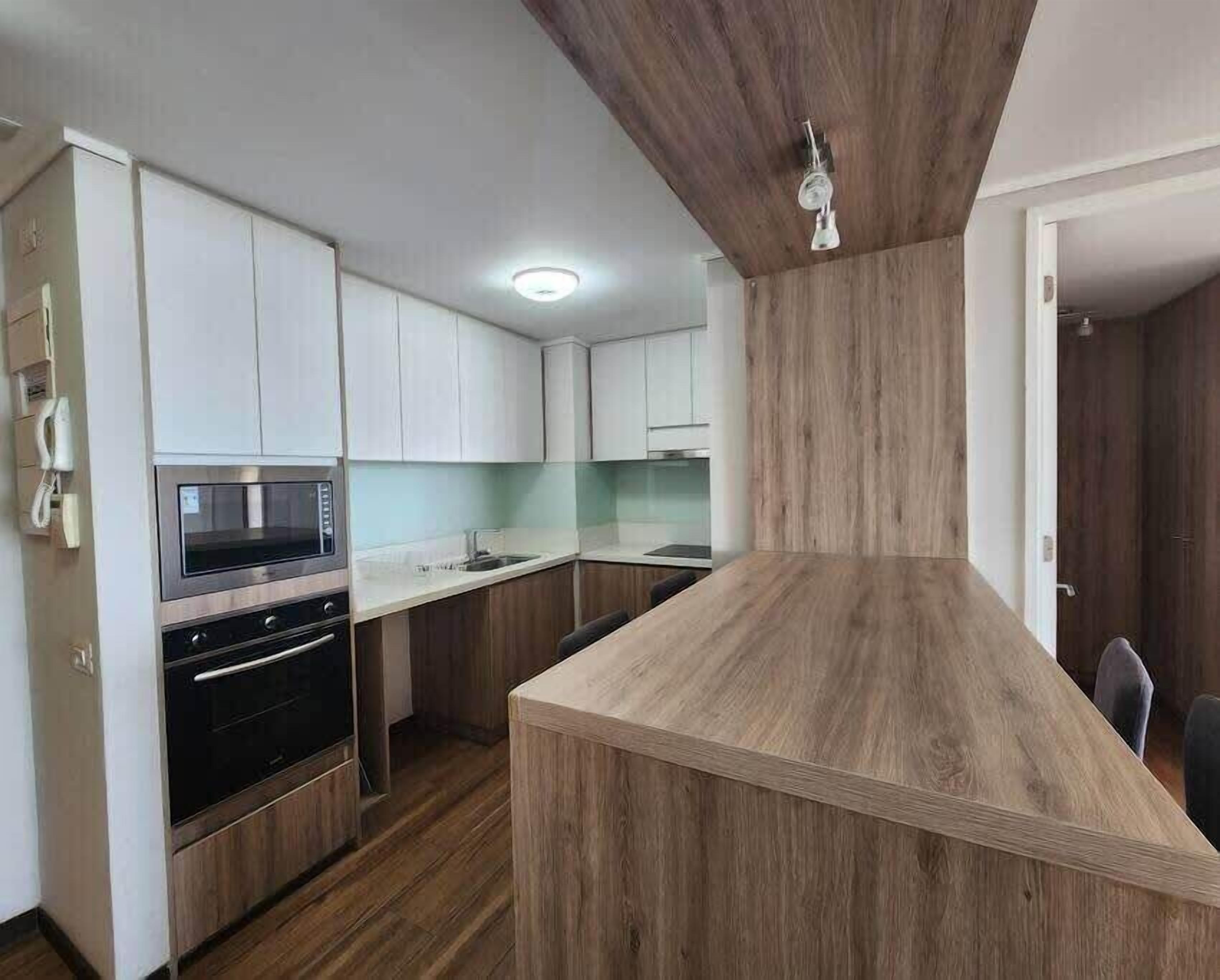 Une cuisine moderne avec des armoires blanches, un four encastré et un îlot central en bois.