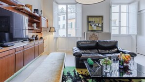 Ein modernes Wohnzimmer mit Ledersofa, Flachbildfernseher, Holzausbau und einem großen Fenster.