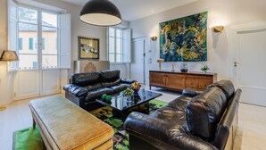 Ein Wohnzimmer mit einer schwarzen Ledersofa, einem Holztisch und einem großen Gemälde an der Wand.