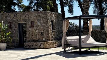 A stone building with a pool, a canopy bed, and a potted plant.