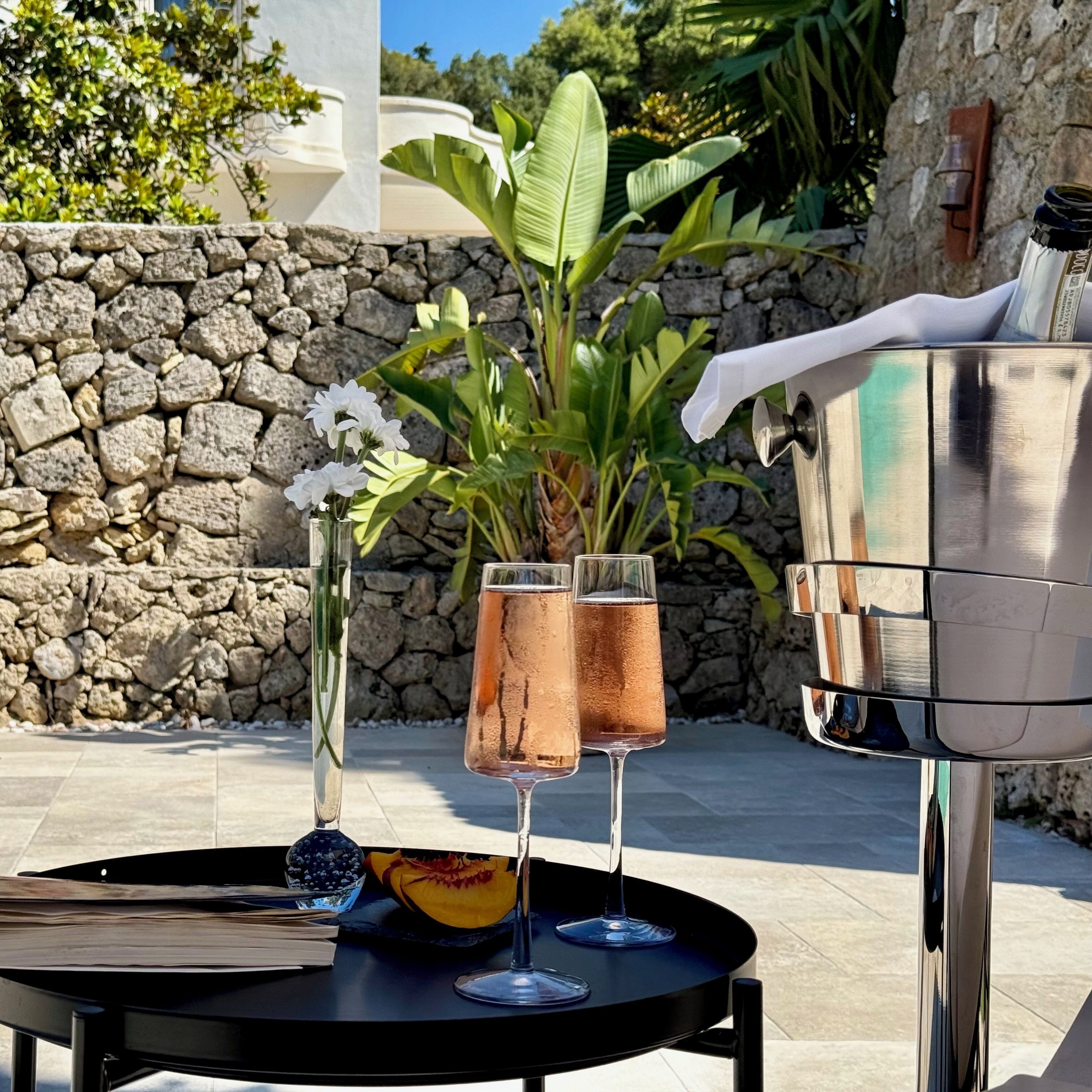 A table with two glasses of rosé wine, a half-cut pumpkin, and a bottle of champagne.