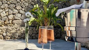 Un tavolo con due bicchieri di vino rosato, una zucca tagliata a metà e una bottiglia di champagne.