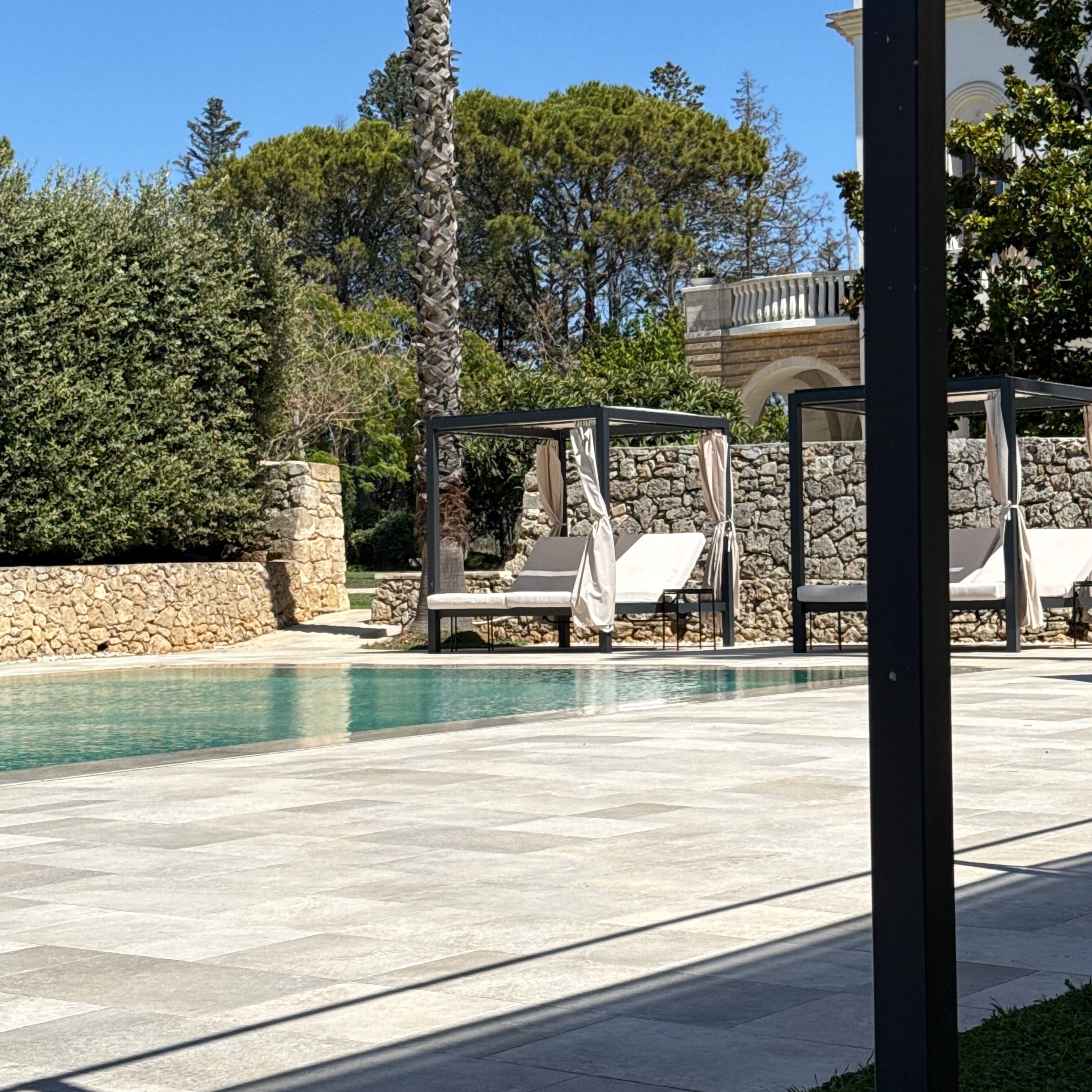 A pool area with lounge chairs and a pergola structure.