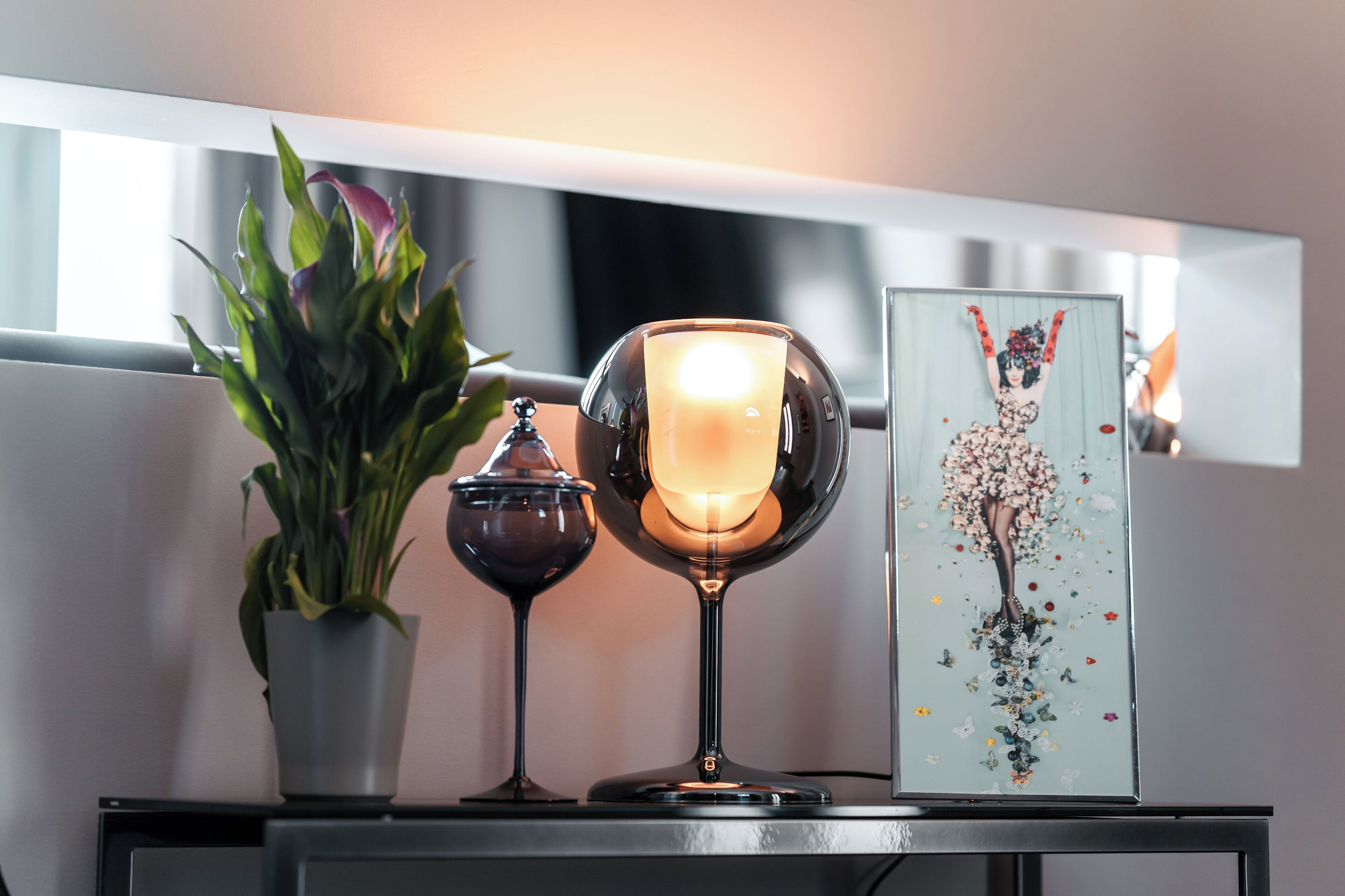 A table with a potted plant, a candle, and a framed artwork.