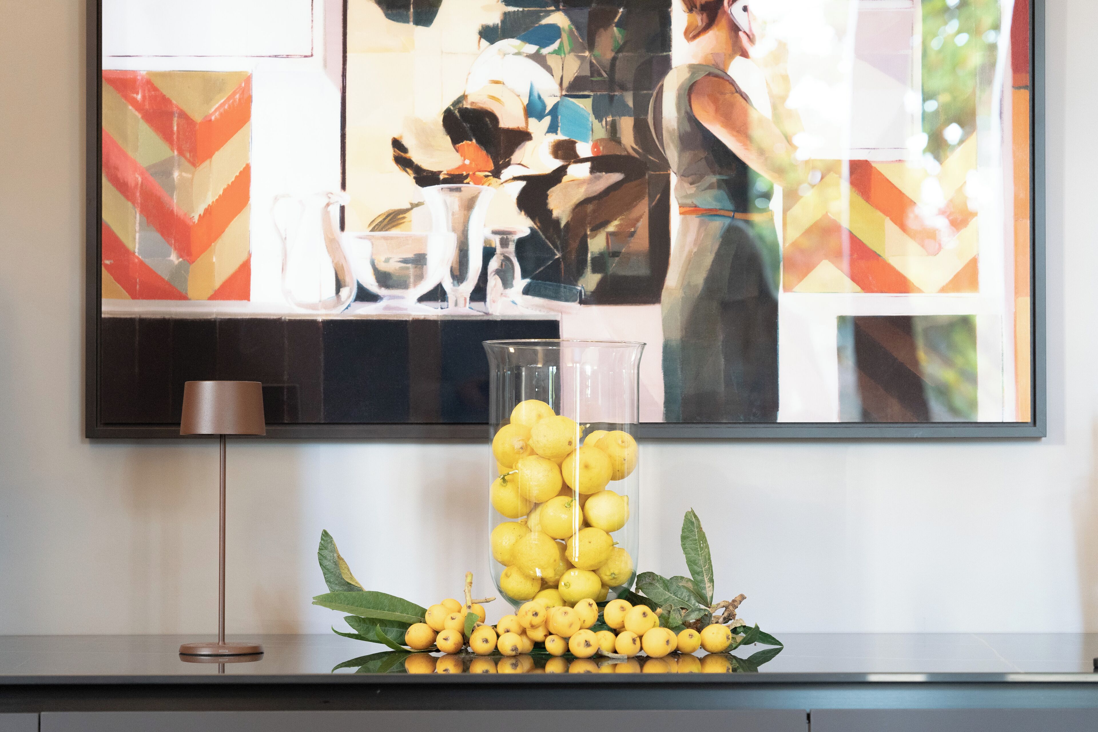 Una encimera de cocina con un jarrón de vidrio lleno de limones y una lámpara.