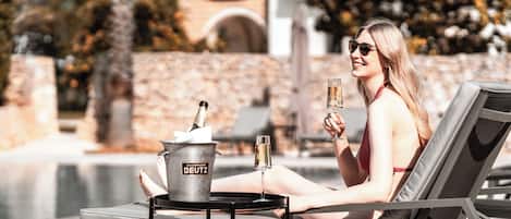 Een buitenzwembad, parasols bij het zwembad en ligstoelen