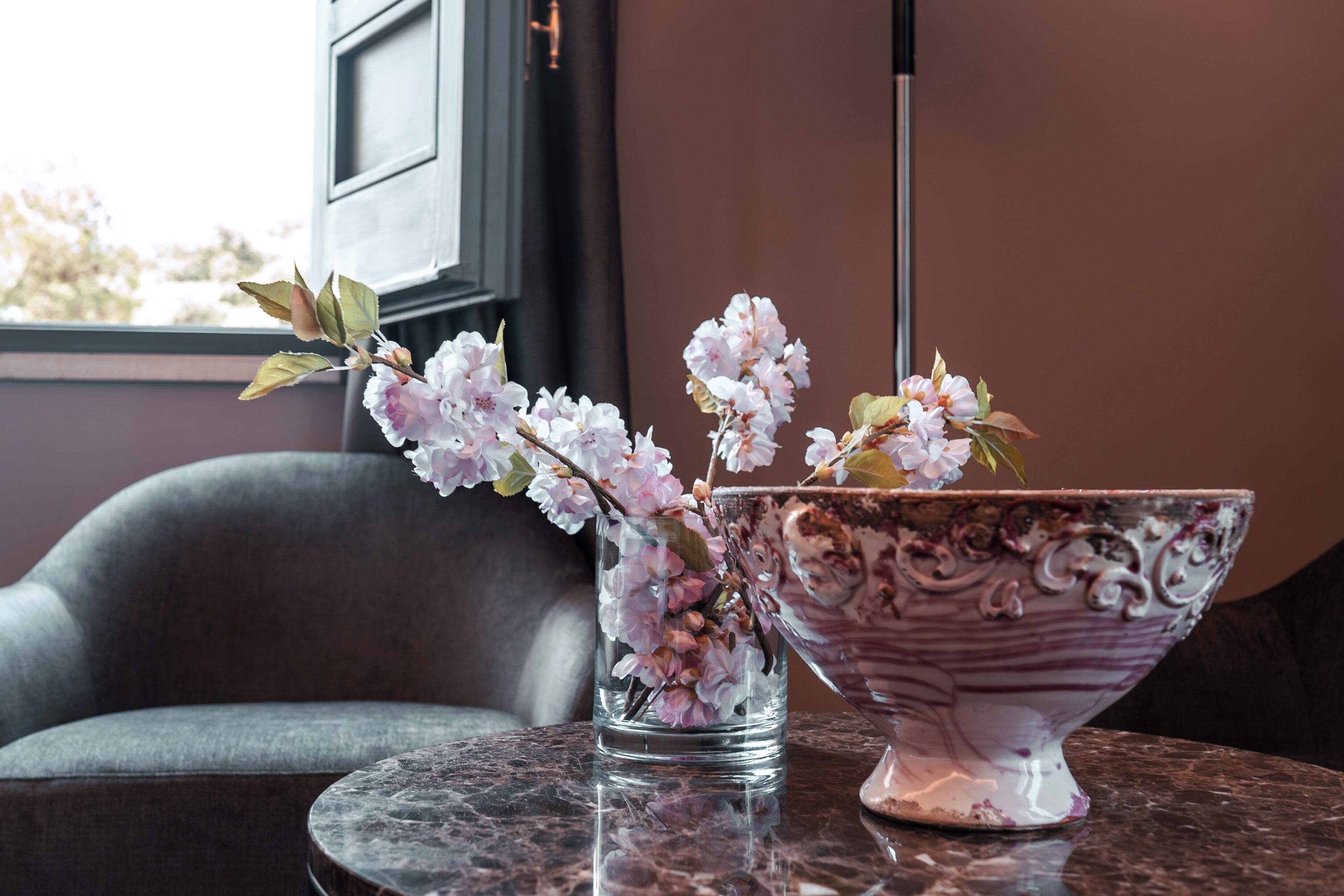 A table with a glass vase and a decorative bowl containing pink flowers.