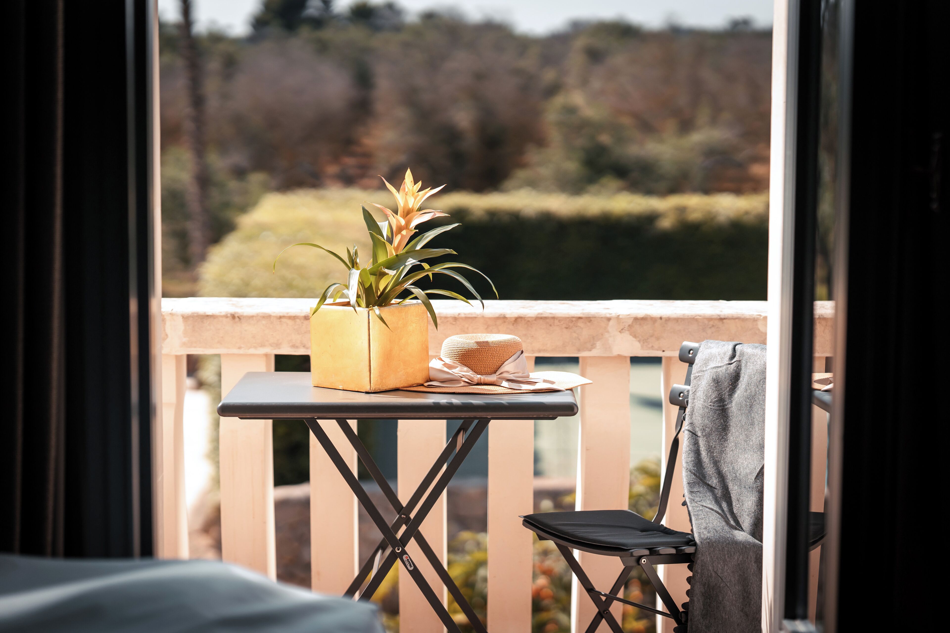 A balcony with a small table, a chair, and a potted plant.