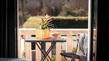 A balcony with a small table, a chair, and a potted plant.