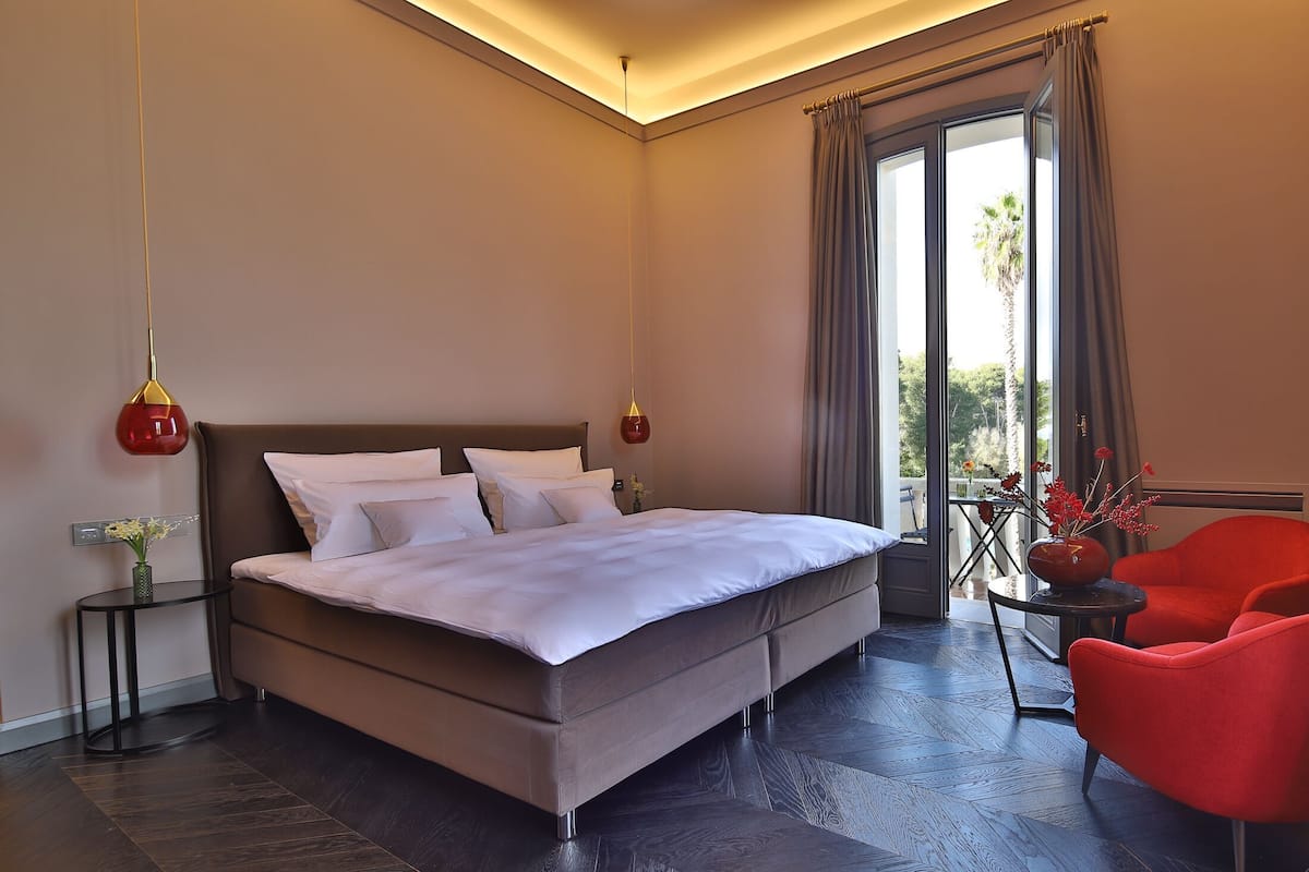 Un dormitorio moderno con una cama grande, una silla roja y vistas al exterior.
