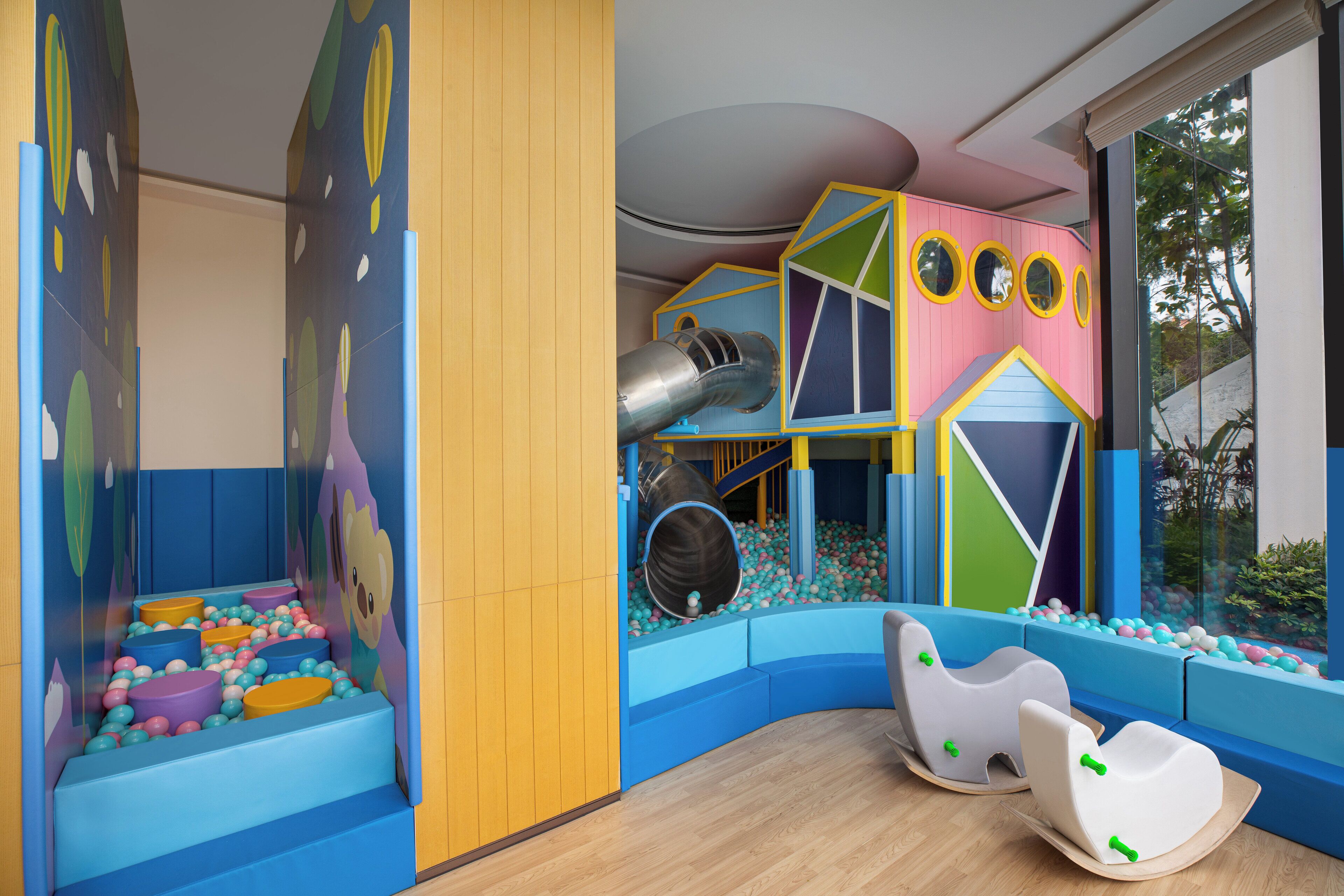 Zona de juegos infantiles con tobogán, piscina de pelotas y estructuras para escalar.