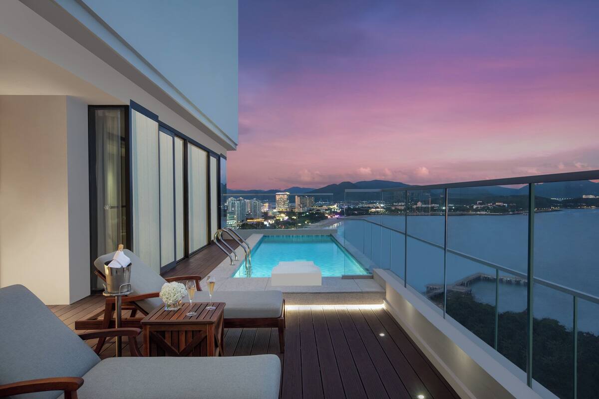 Ein Balkon mit Pool, Sitzgelegenheiten und Blick auf die Stadt im Abenddämmerung.