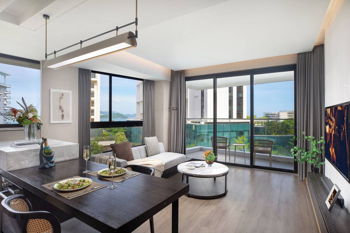 Ein modernes Wohnzimmer mit Essbereich, großen Fenstern und einem Balkon mit Stadtblick.