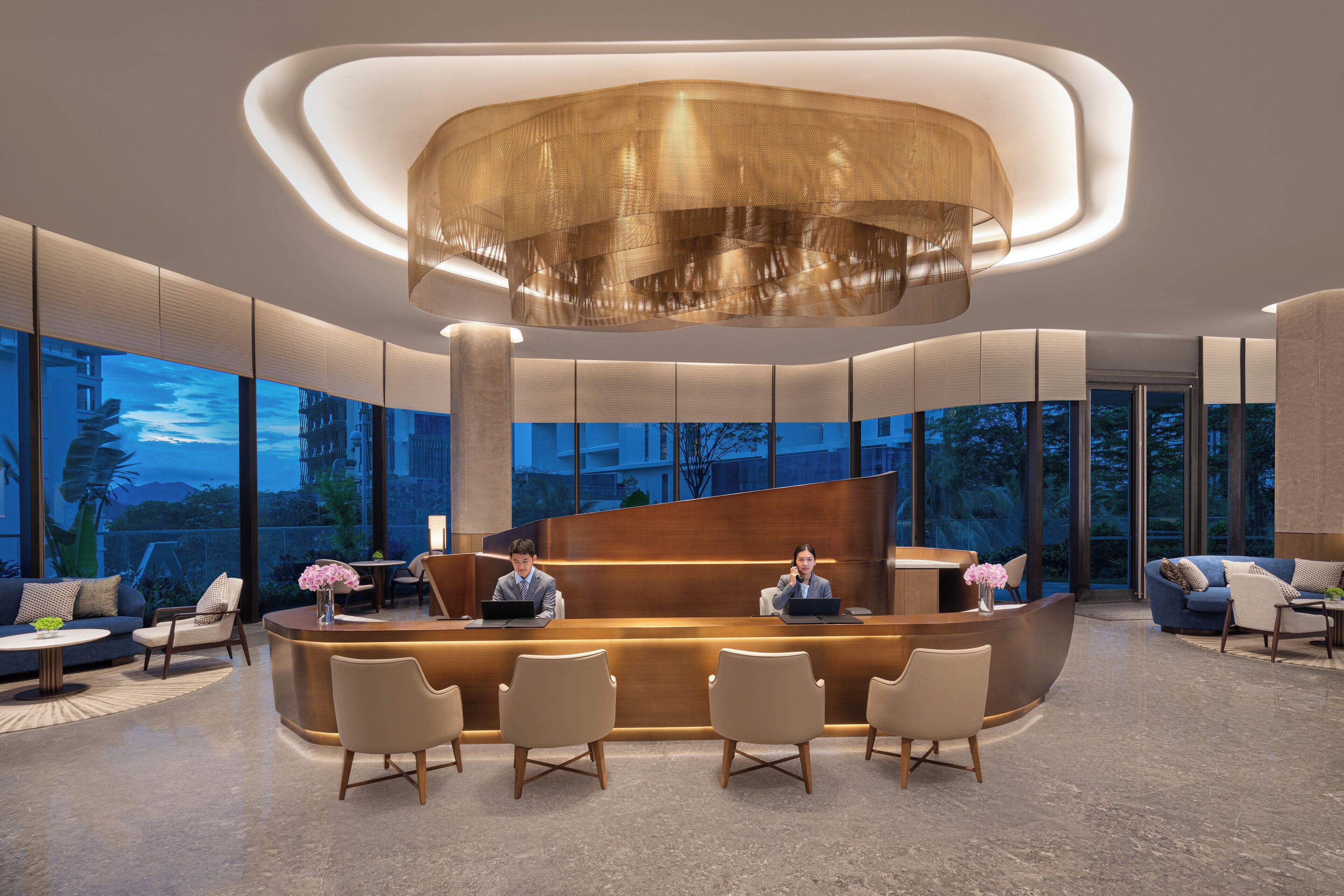 Un área de recepción moderna con un mostrador curvo, asientos y ventanas amplias que ofrecen vistas al exterior.