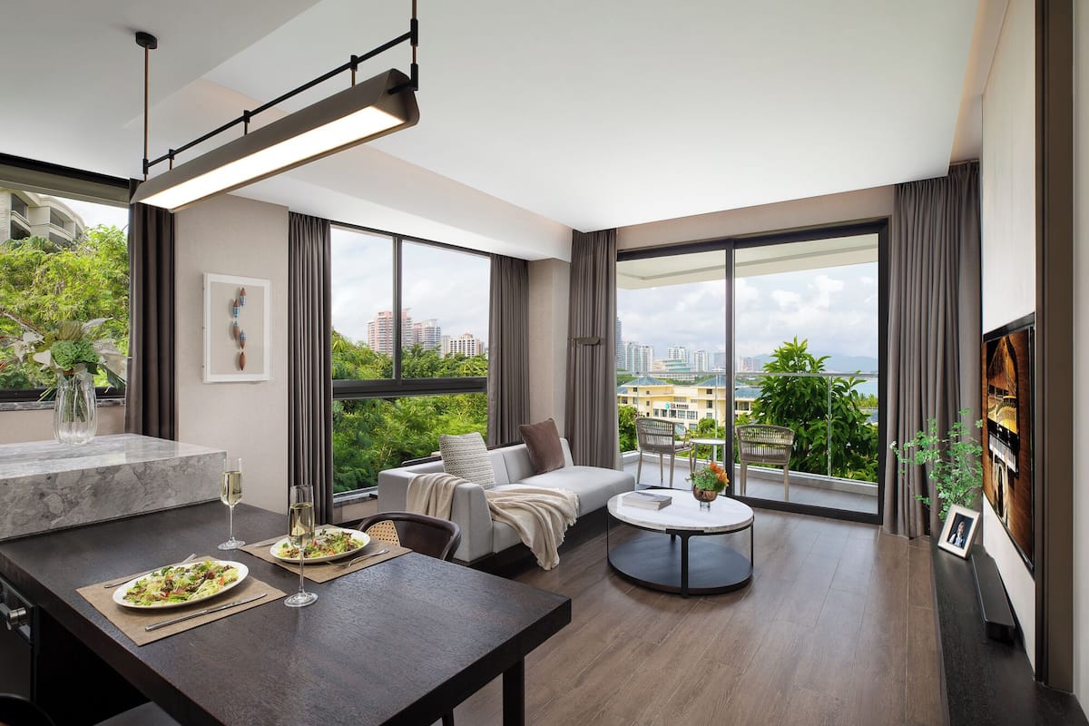 Ein modernes Wohnzimmer mit Essbereich, großen Fenstern und Blick auf die Stadt sowie einer gemütlichen Sitzecke.