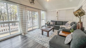 A spacious living room with a dark wood floor, a grey sofa, a coffee table, and a ceiling fan.