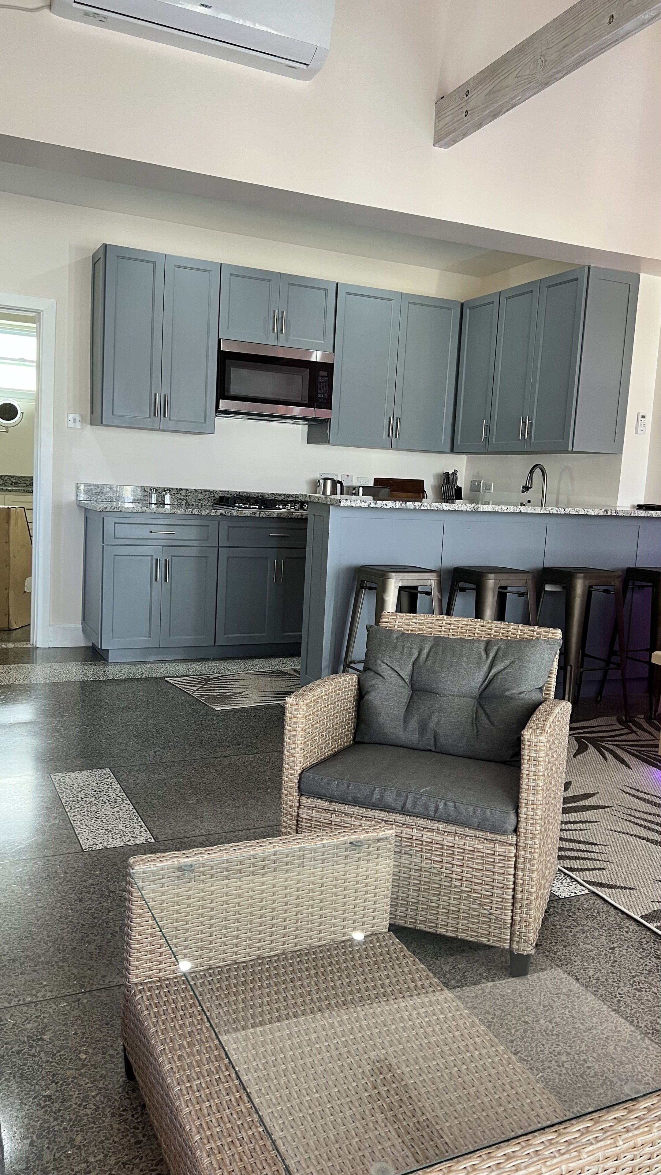 A modern kitchen with grey cabinets, a built-in microwave, and a stainless steel range hood.