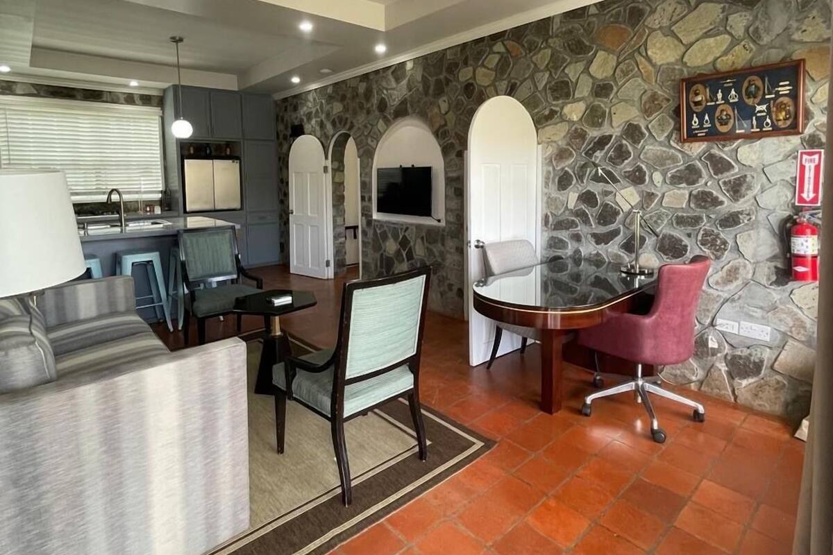 A modern kitchen with a stone accent wall, a dining area with a table and chairs, and a built-in TV.