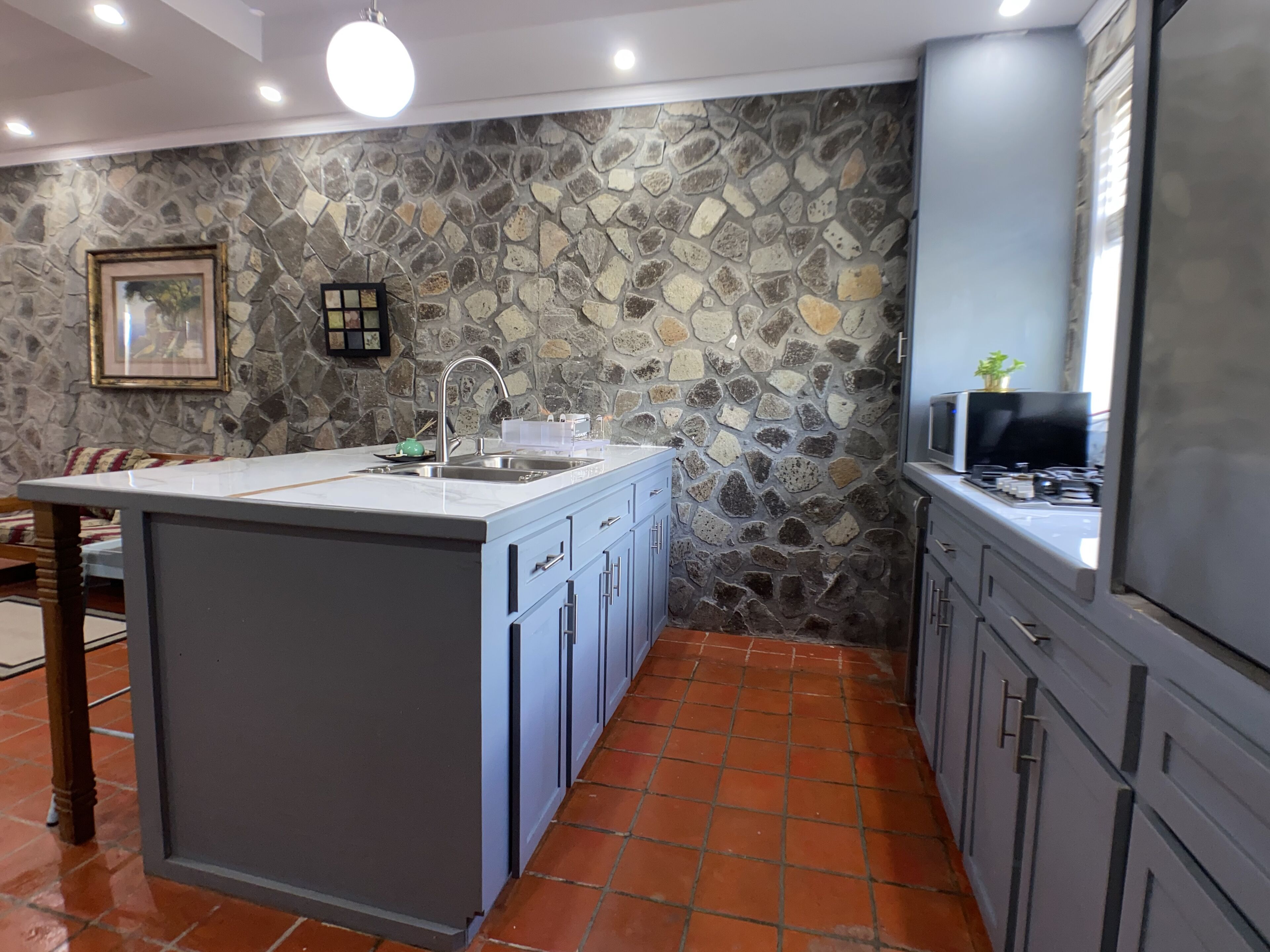 A kitchen with a stone backsplash, a sink, and cabinets.