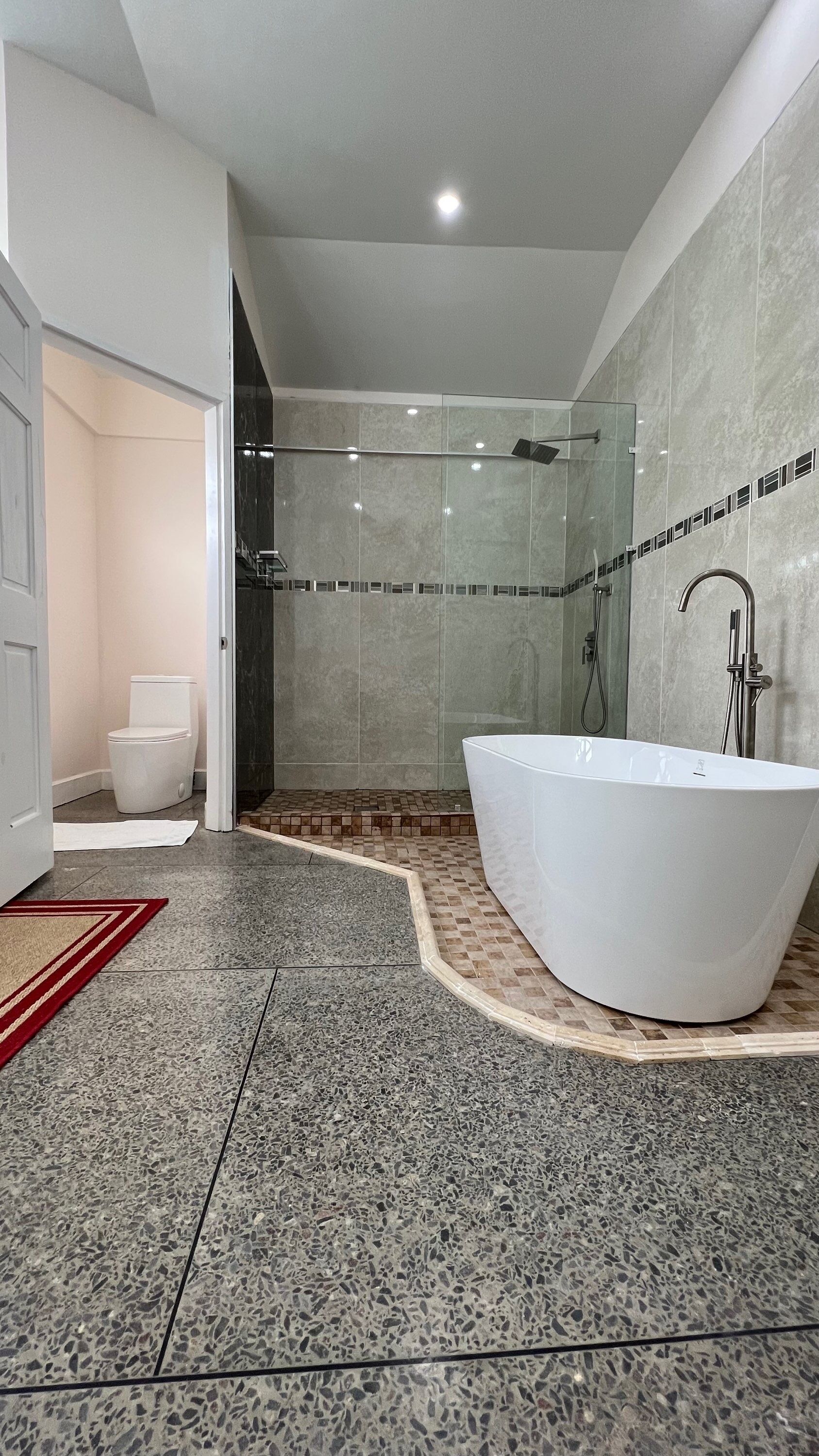 A modern bathroom with a freestanding bathtub, a glass-enclosed shower, and a toilet.