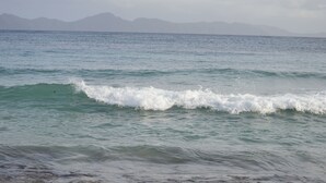 A beach with waves and distant mountains. - Stonetrail (Villa)