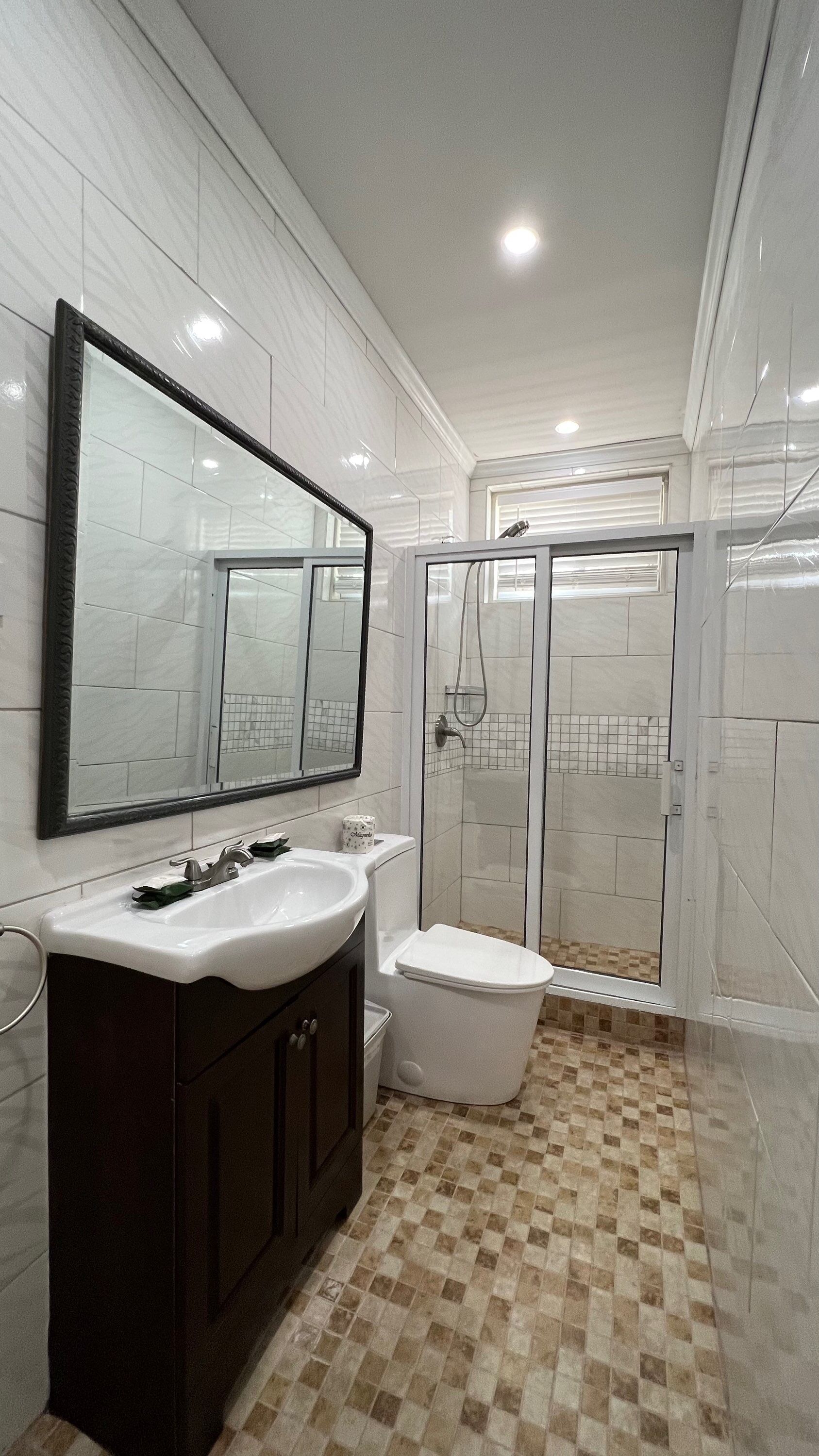 Ein Badezimmer mit weißem Waschbecken, Toilette und Duschbereich.