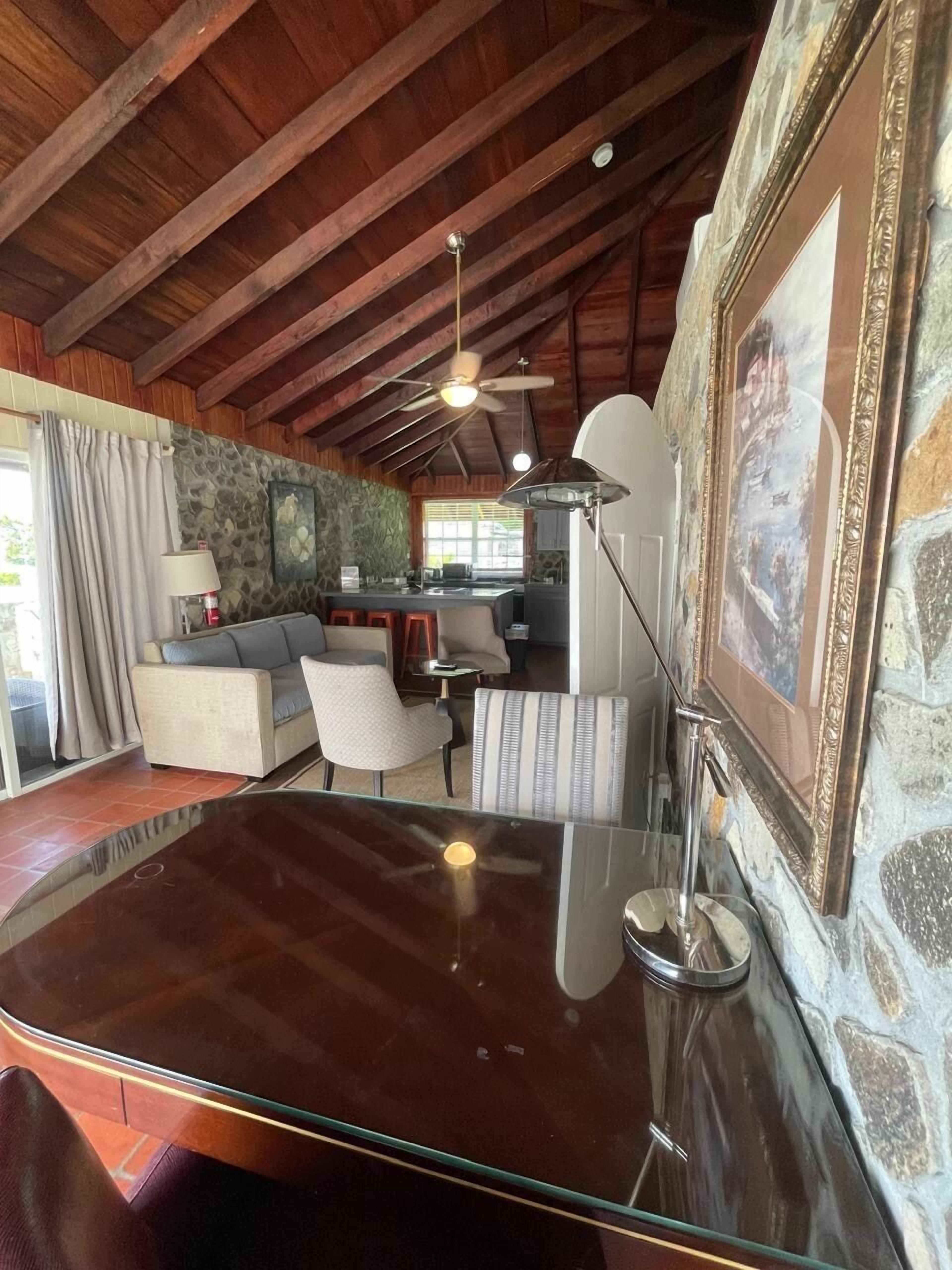 Un vaste espace de vie comprenant un salon avec une table basse en verre, un canapé et un coin repas.