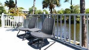 A deck with two wicker chairs and a small table, overlooking a body of water with trees in the background. - 3 BR Beach House in Surfside Beach! Raycliff at the Beach (Surfside Beach)