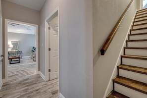 Staircase leads to a spacious area with a door and a herringbone-patterned floor.