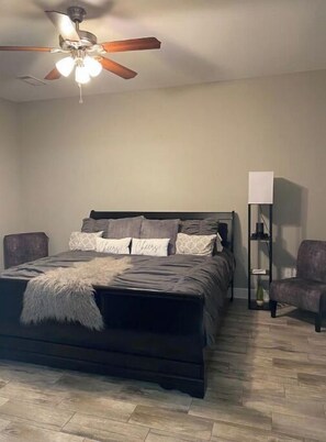 Relax in this serene bedroom with a comfortable dark-colored bed, ceiling fan, and floor lamp.