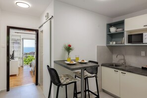 A modern kitchen with a dining area, a view to the outside, and a small island with a sink. - Beslema sea view apartment with balcony (Dubrovnik)