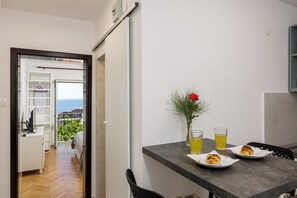 Une cuisine moderne avec une table à manger, deux assiettes de pâtisseries, un vase avec une fleur rouge et deux verres contenant une boisson jaune.