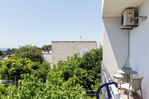 Un balcon donnant sur un immeuble, avec vue sur de la verdure et un appareil de climatisation.