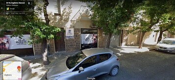 Una vista di una strada con un edificio, auto parcheggiate e alberi.