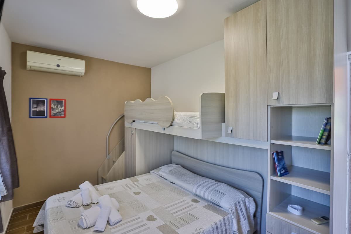 Ein Schlafzimmer mit einem Bett, einem Kleiderschrank, einem Bücherregal und einer Klimaanlage.