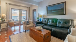 A spacious living room with a leather sofa, a wooden coffee table, and a view of the sea through large sliding doors. - Terracotta Villa 117 Bayfront Fireworks Boat Slip View Space X Hot tub (South Padre Island)