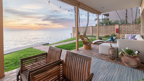 A patio with a view of the sea, wooden furniture, and a white sofa. - Terracotta Villa 117 Bayfront Fireworks Boat Slip View Space X Hot tub (South Padre Island)