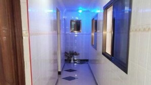 A hallway with a tiled floor, a wooden door on the left, and a window on the right.