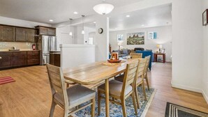 Una cocina moderna con comedor, armarios de madera y un refrigerador de acero inoxidable.