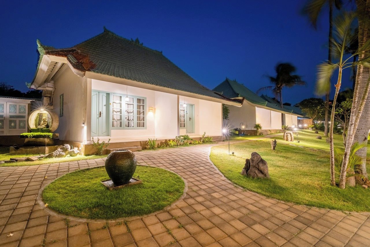 A traditional building with a tiled roof, a paved pathway, and a well-maintained lawn.