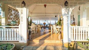 An open-air covered patio with wooden flooring, white railings, and a central table with chairs.