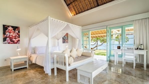 A four-poster bed with a canopy, a bedside table, a bench, and a desk with chairs.